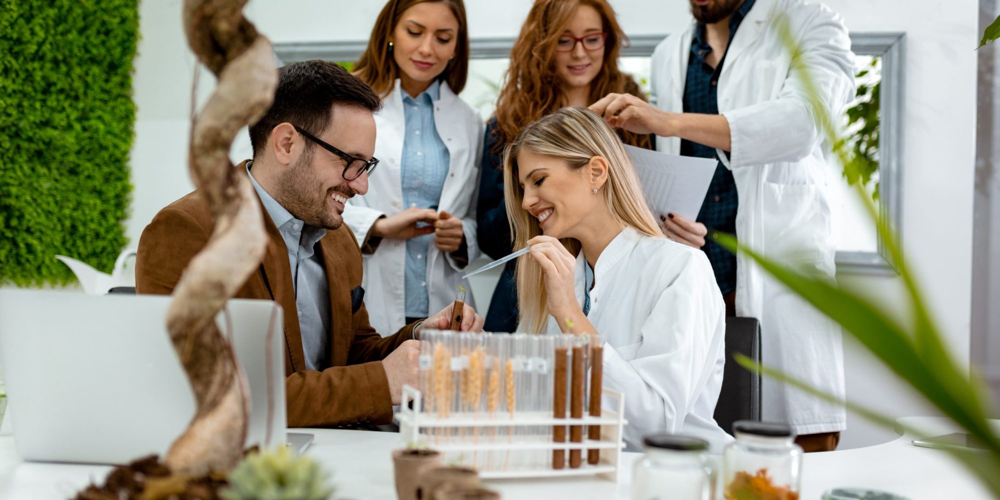 University colleague biologists taking experiment on sprout and checking the analysis of the sample of plant in the lab tube.